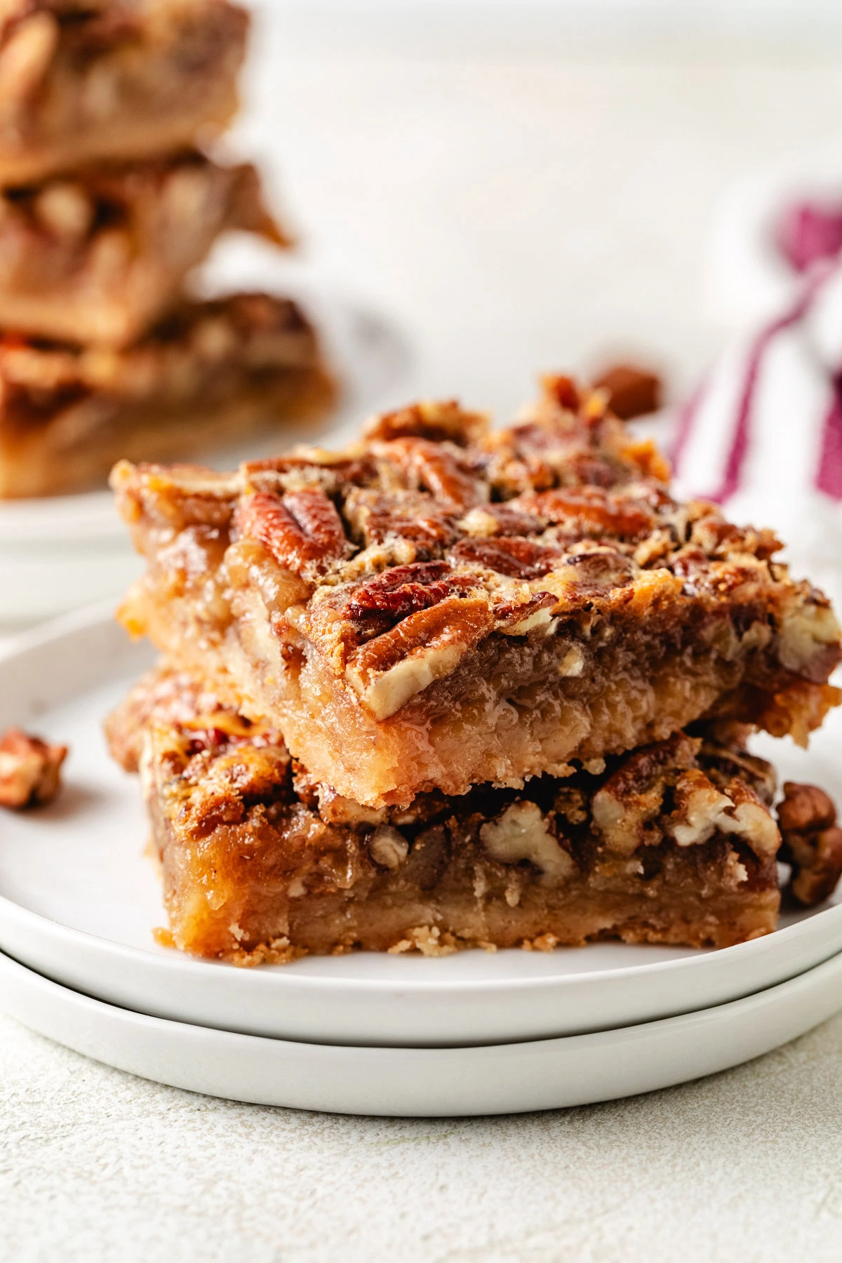 Pecan bars stacked on a white plate.
