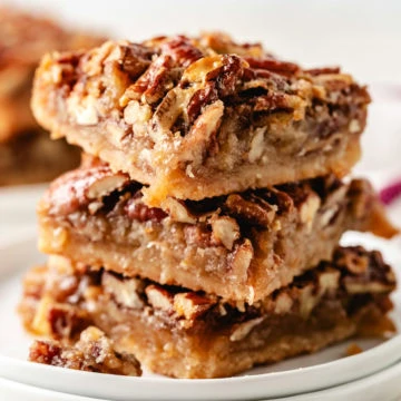 Stack of pecan pie bars on plates.