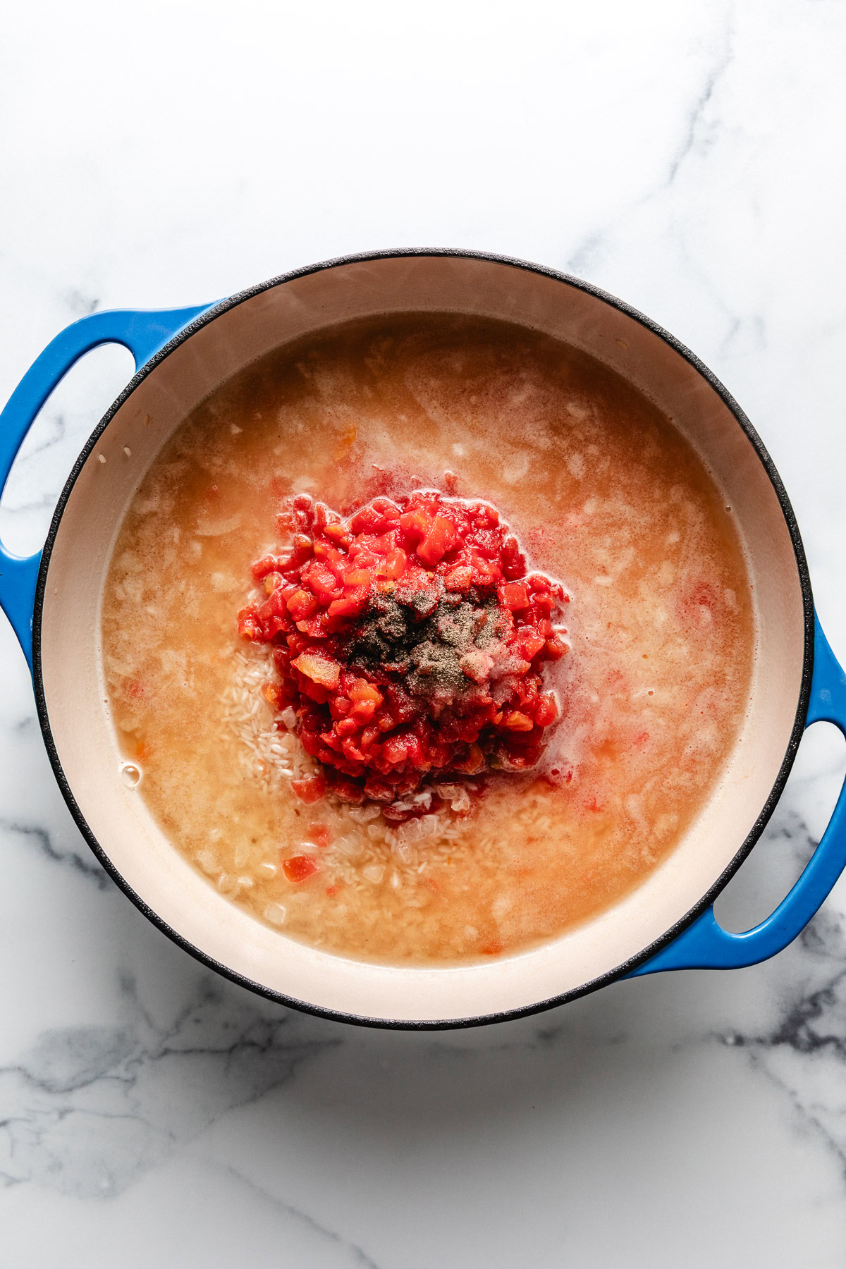 Broth, rice, tomatoes, and seasonings in a skillet.