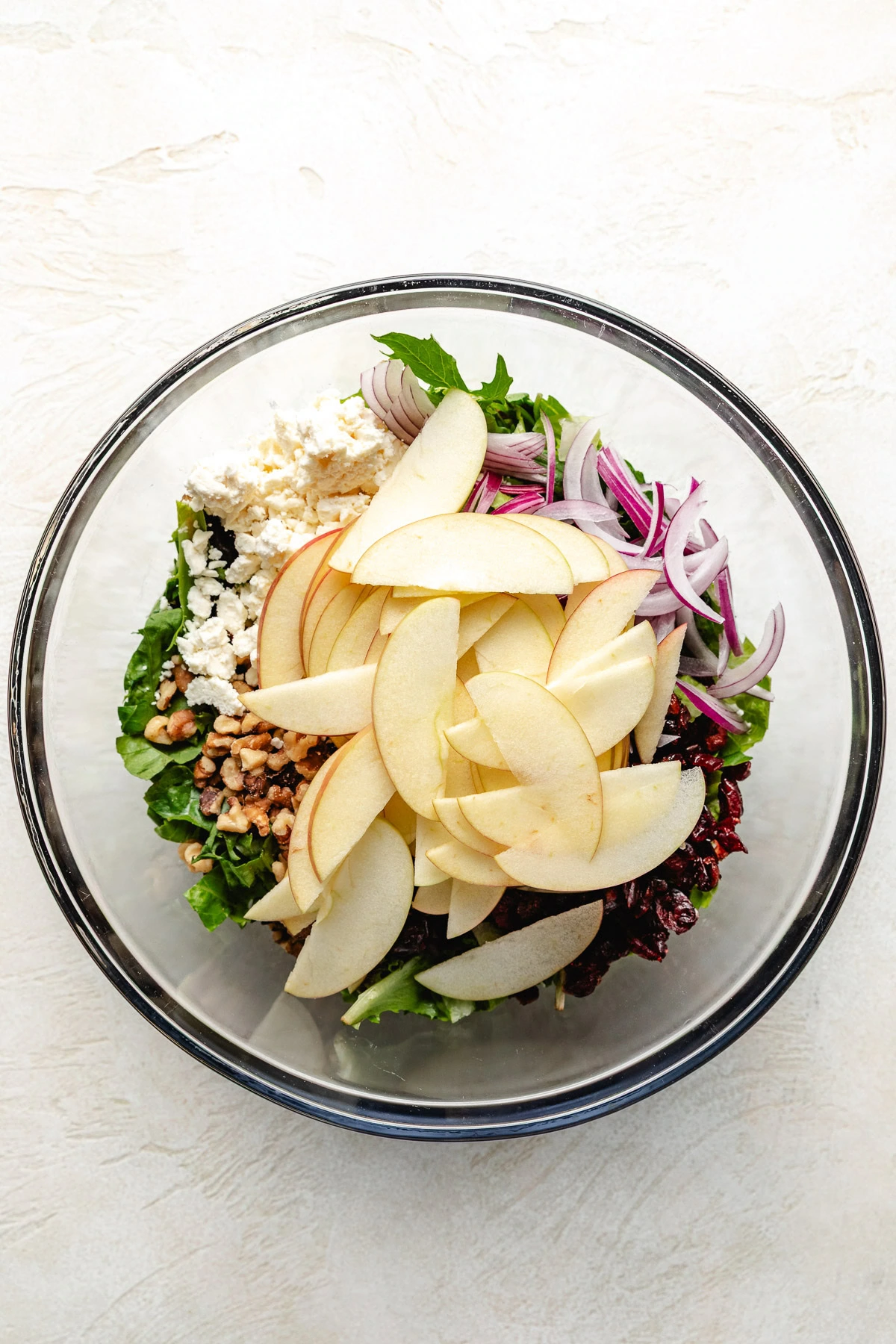Ingredients for apple cranberry walnut salad in a bowl.