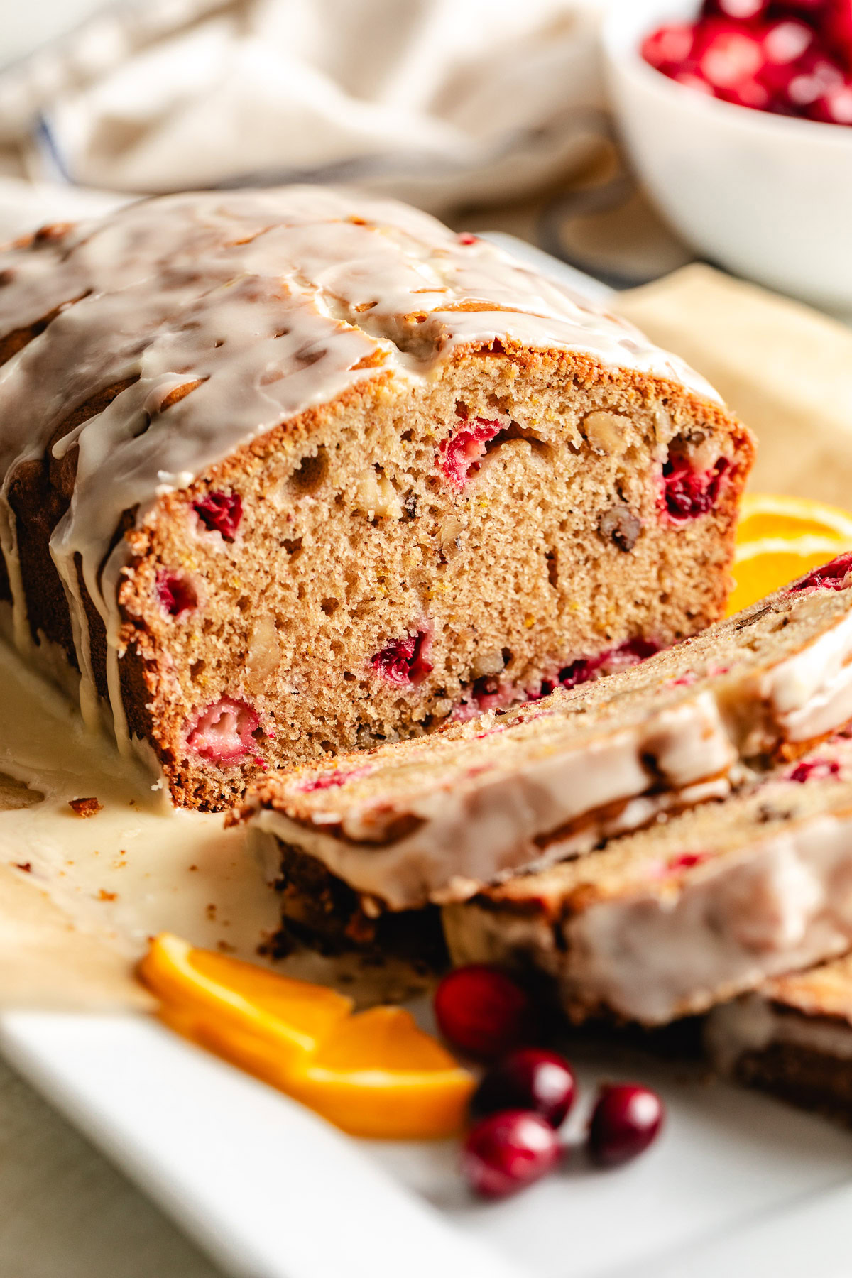 Cranberry Nut Bread Cranberry bread with glaze on parchment.