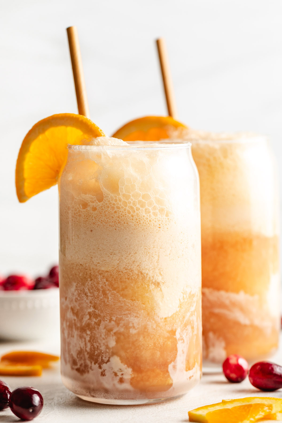 Orange slices on glasses of cranberry orange ice cream soda.