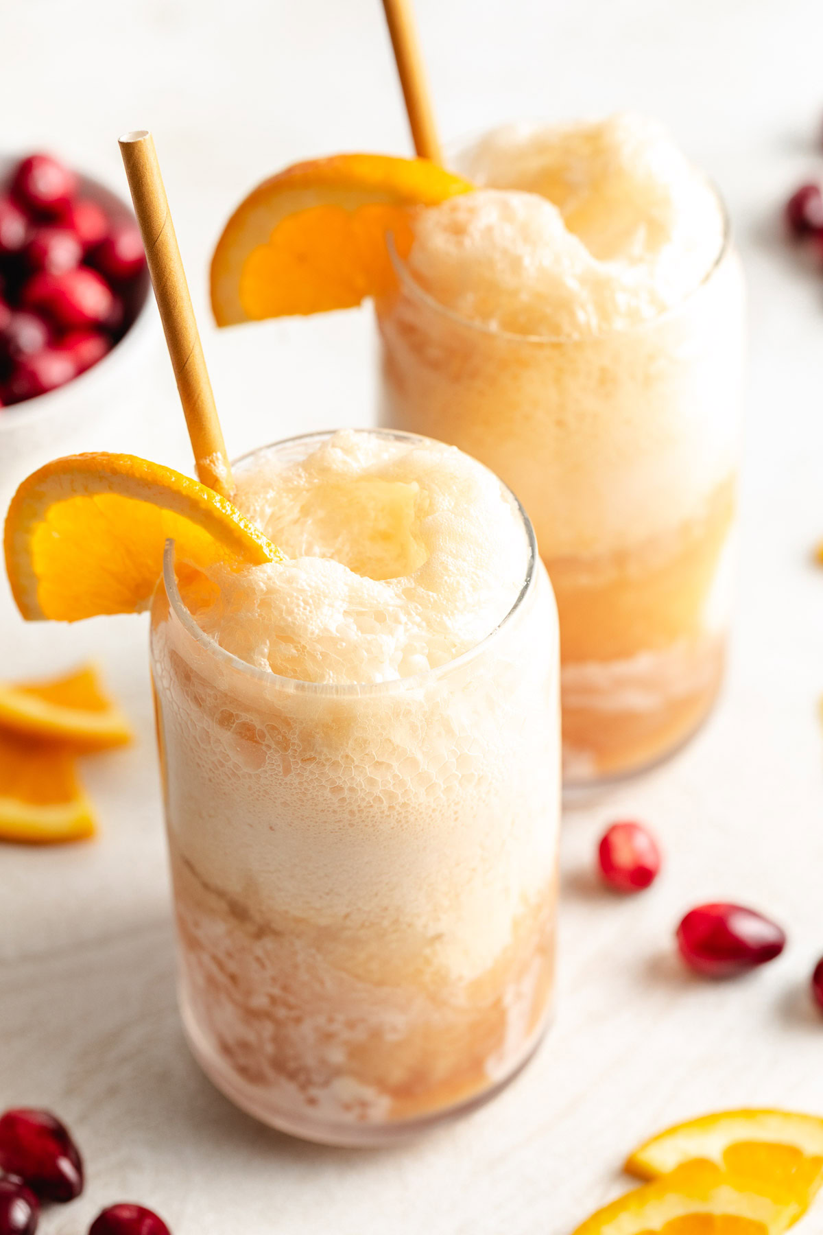 Two glasses of cranberry orange soda with ice cream.