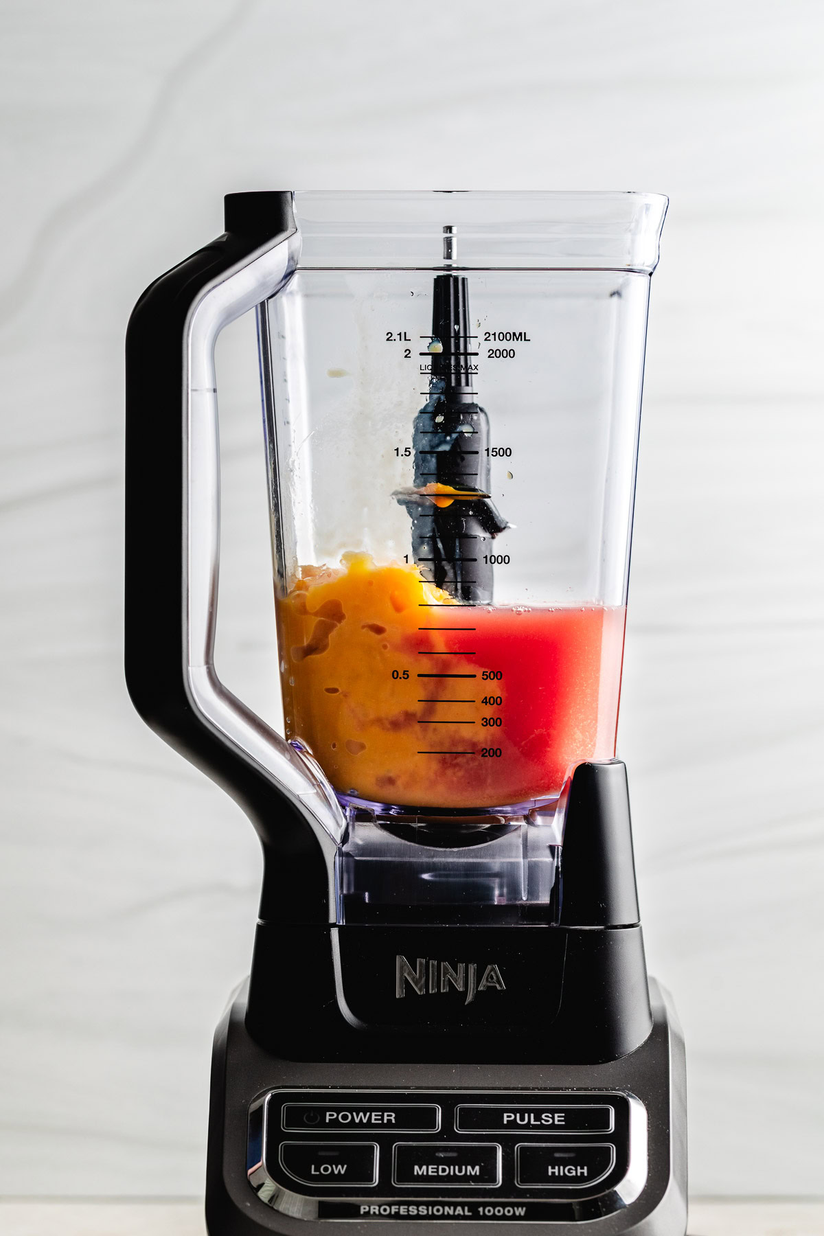Cranberry juice and orange concentrate poured in a blender.