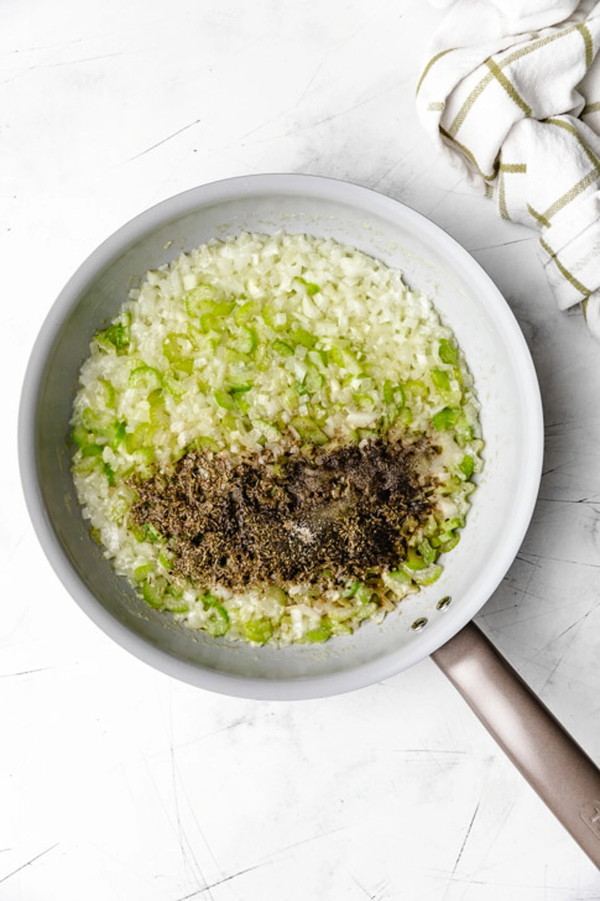 Herbs added to a pan of celery and onions.