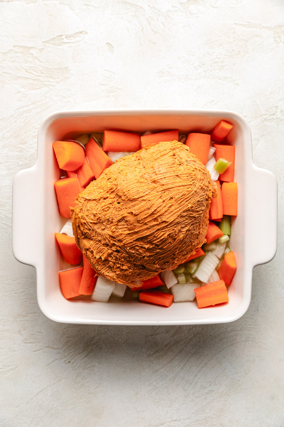 Buttered turkey in a pan over veggies.