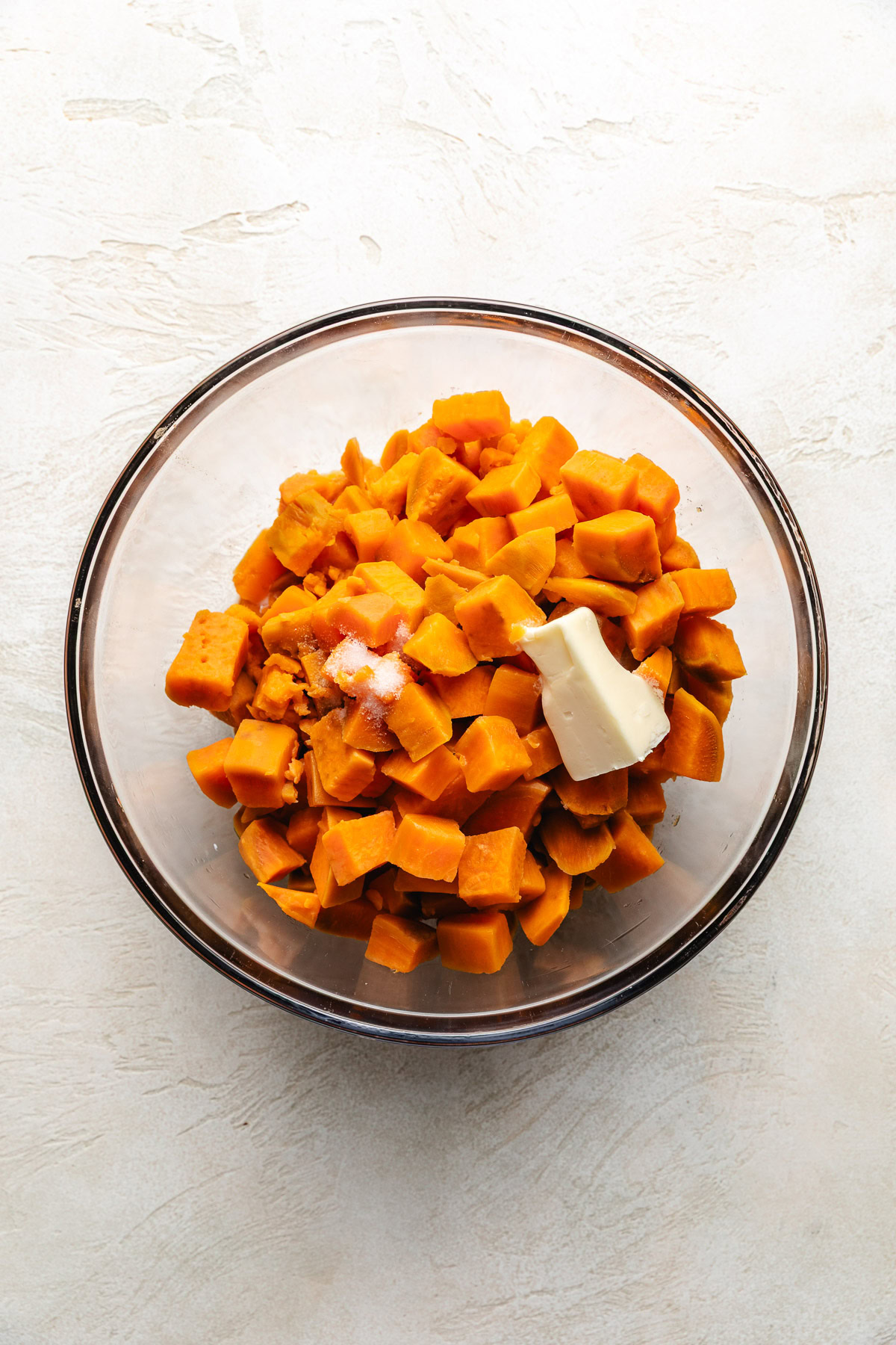 Mixing bowl with sweet potatoes, butter, salt, and milk.