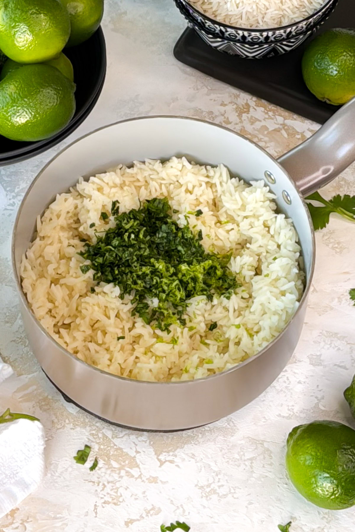 Saucepan of cilantro lime rice being finished with chopped cilantro and fresh lime zest.