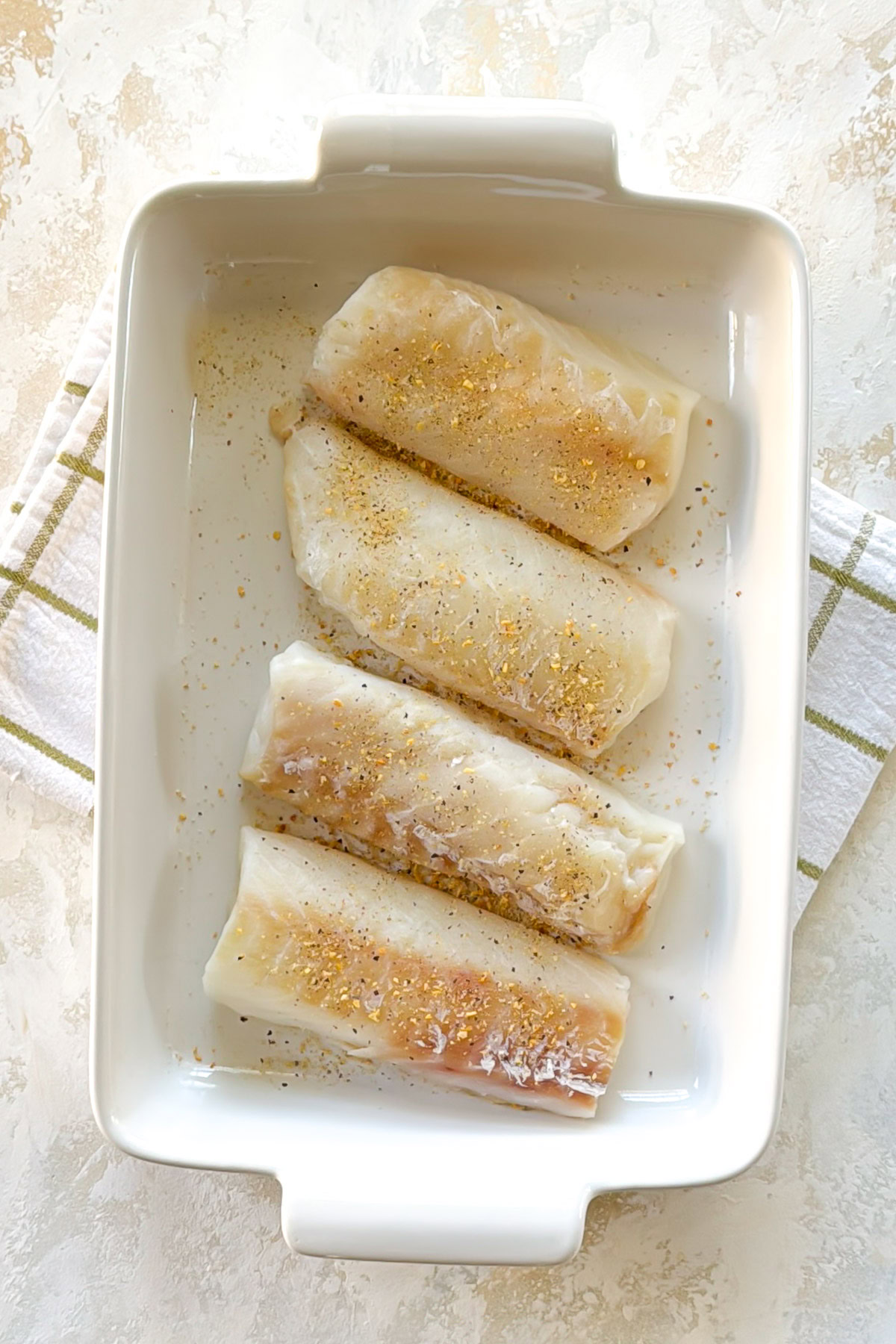 Lemon Garlic Butter Baked Cod Raw cod fillets in baking dish.