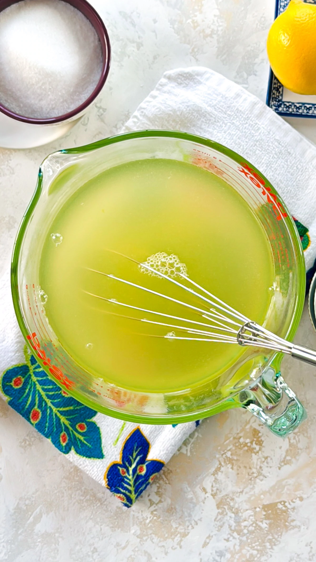 Fresh lemon juice mixture in a glass measuring cup with a whisk.