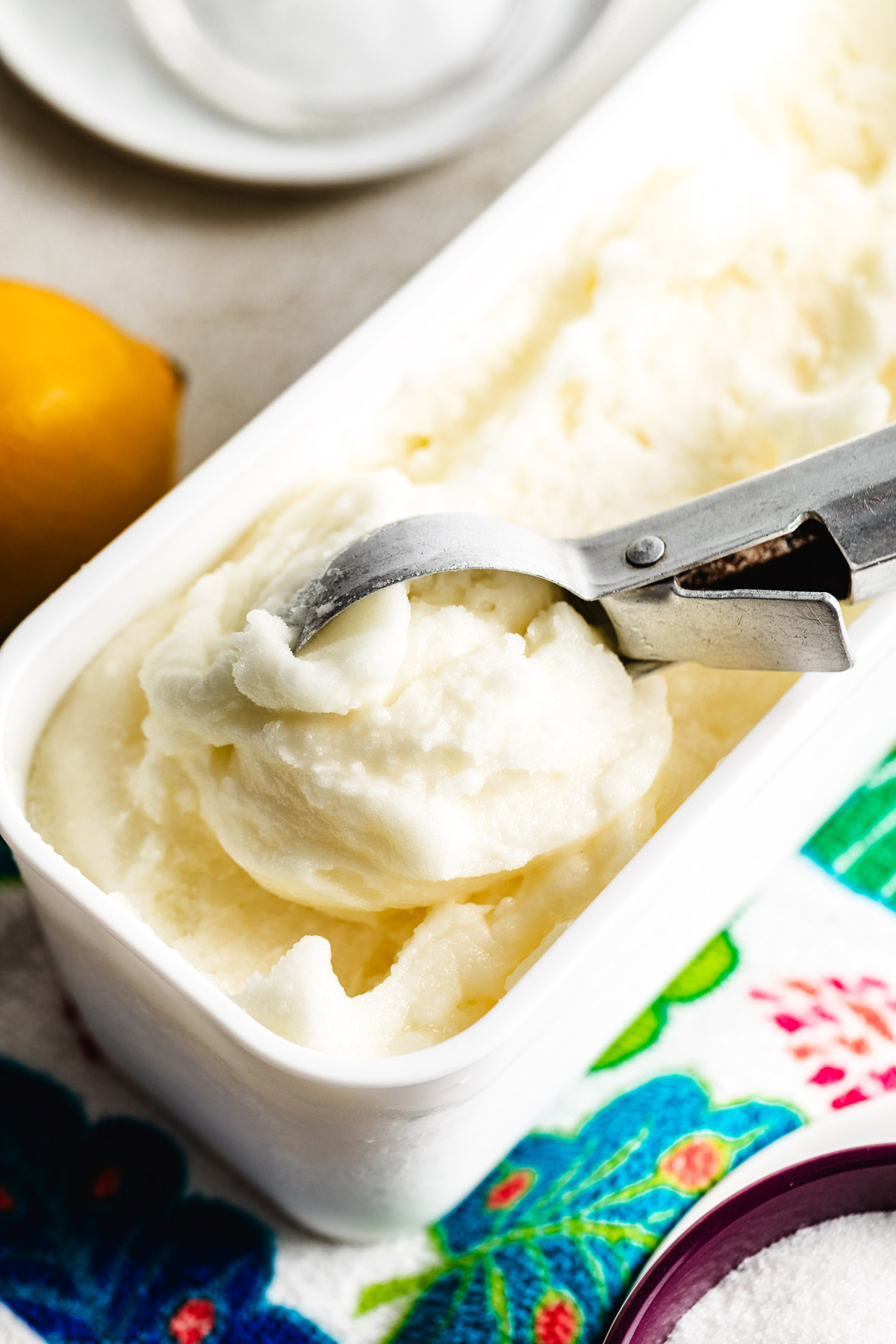 Lemon sorbet being scooped from a loaf-style container with a metal ice cream scoop.