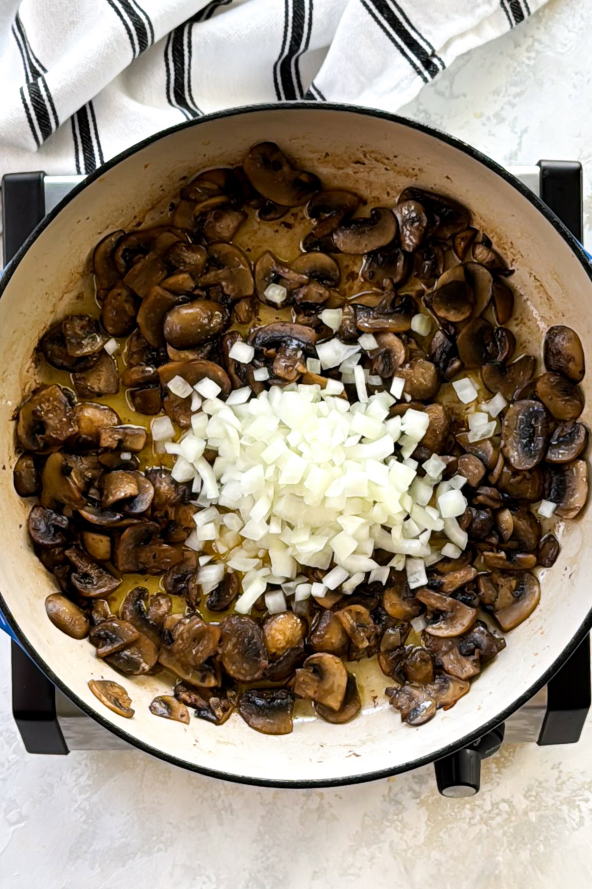 Mushrooms and onions cooking down in a Dutch oven.