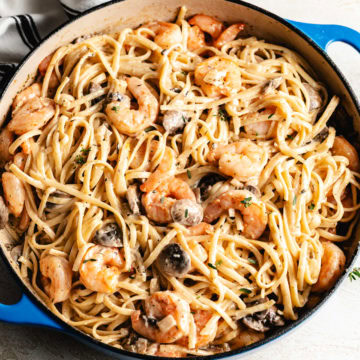 Mushroom shrimp pasta in a blue skillet with creamy sauce and sliced mushrooms.