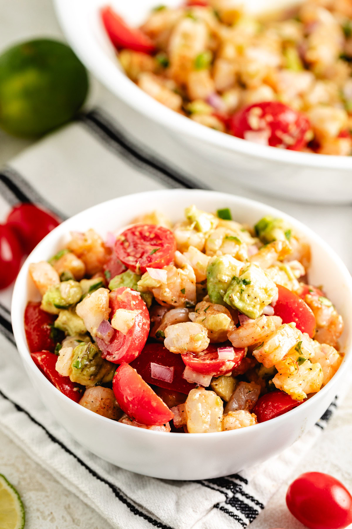 Bowl of shrimp and avocado salad with tomatoes and diced red onion.