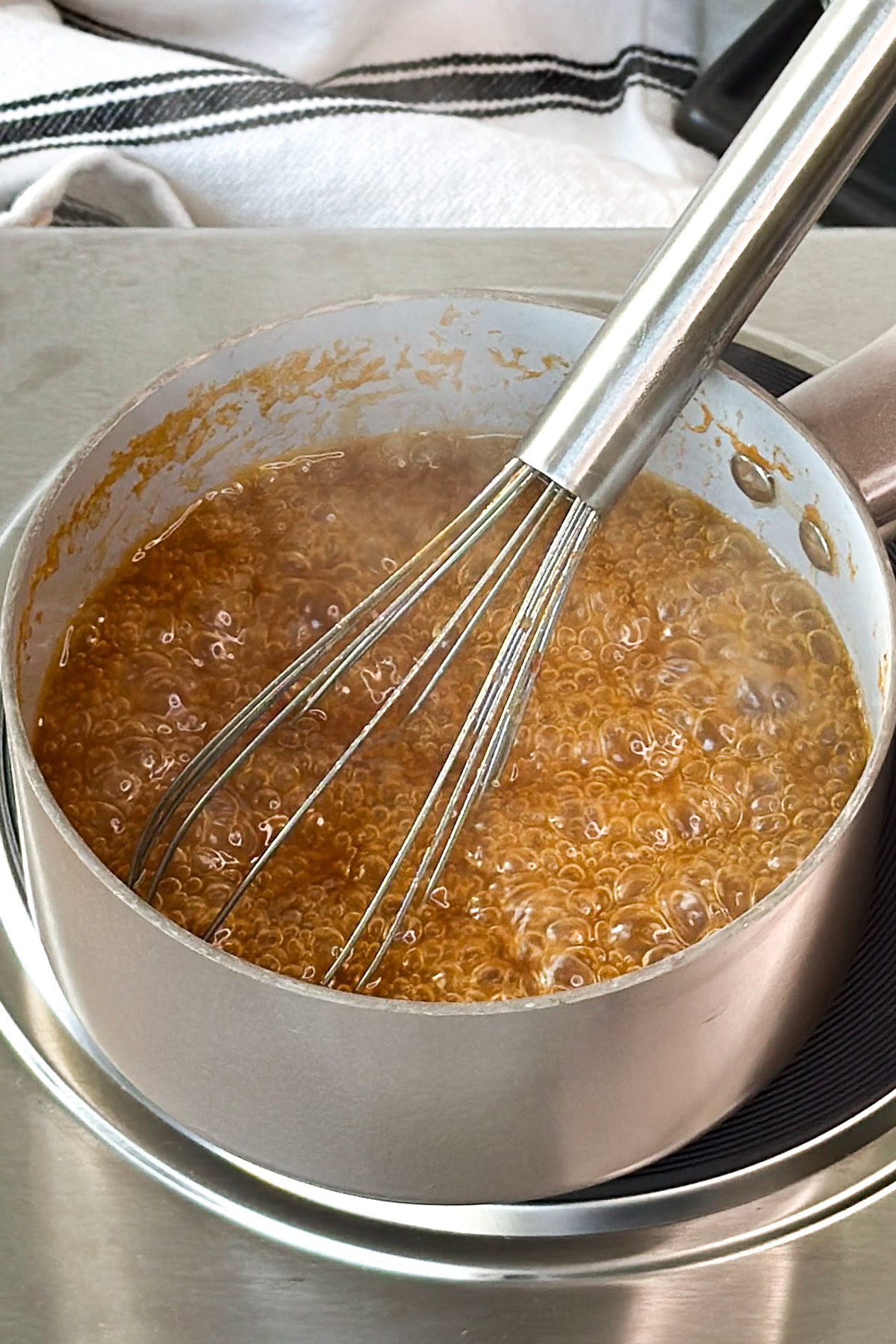 Simmering sauce in a pot with whisk.