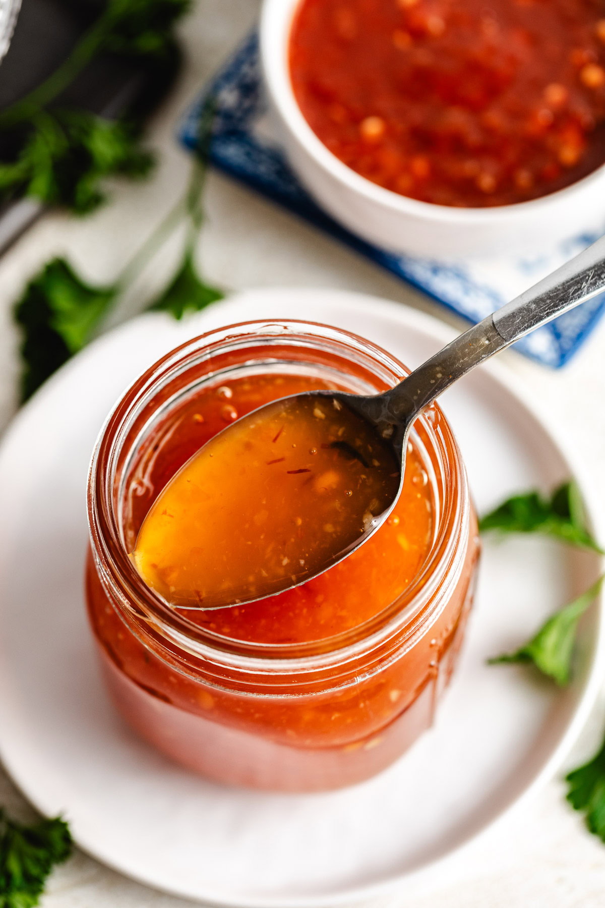 Mason jar of chili sauce with spoon.
