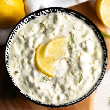 Creamy tartar sauce with dill relish in a patterned bowl, topped with a lemon slice and fresh dill.