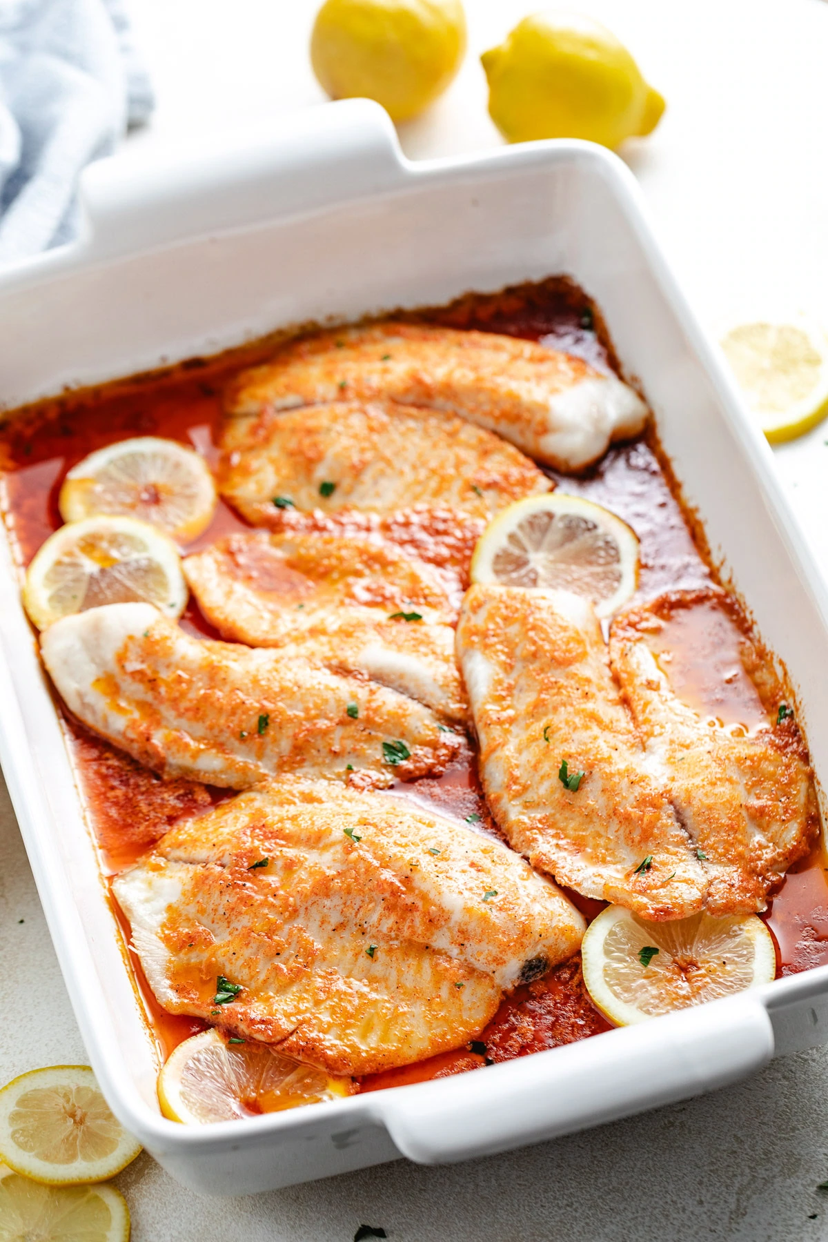 Baked white fish and lemons in a pan.