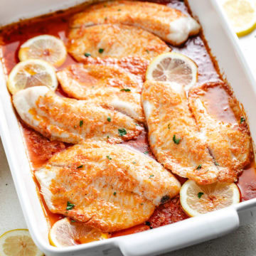 Close up view of fresh baked tilapia in a white dish.