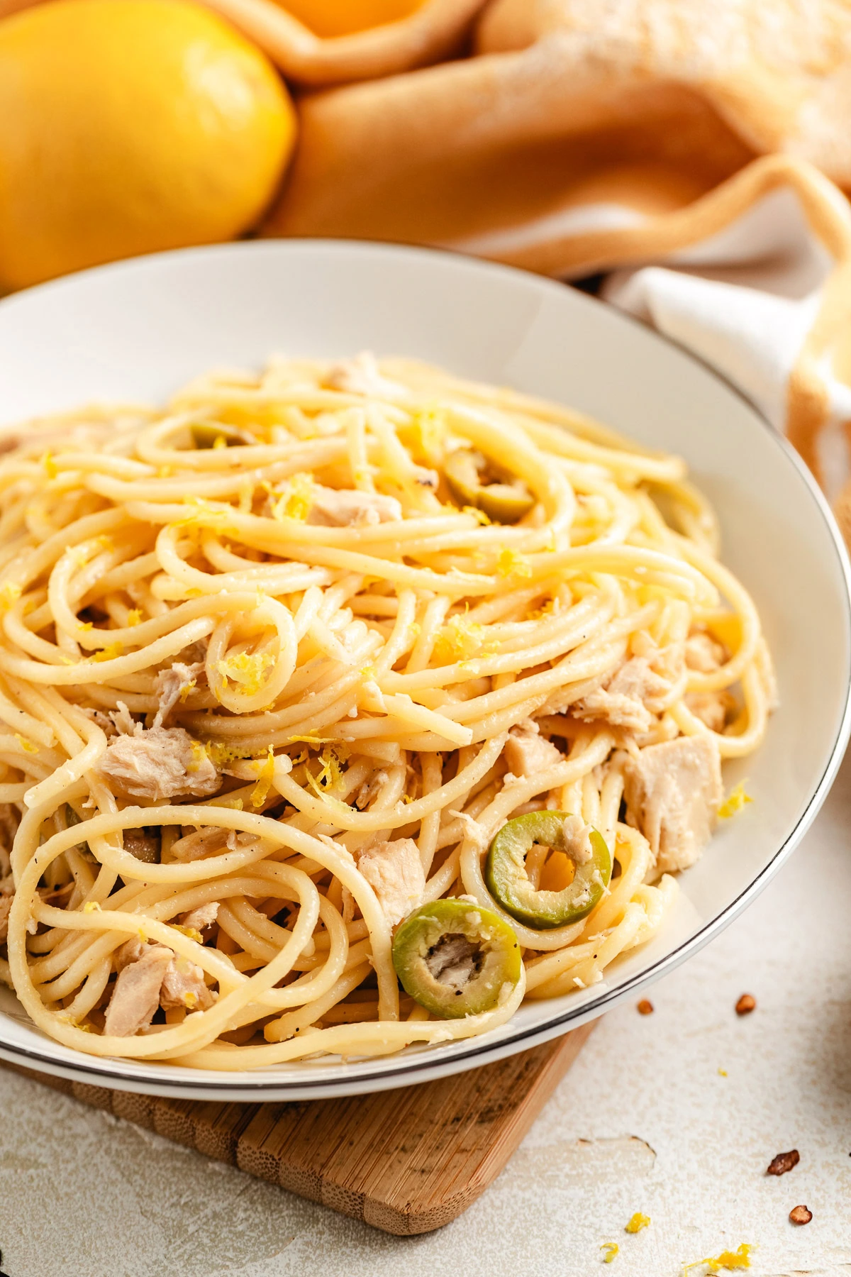 Close view of canned tuna pasta twirled in a shallow white bowl.