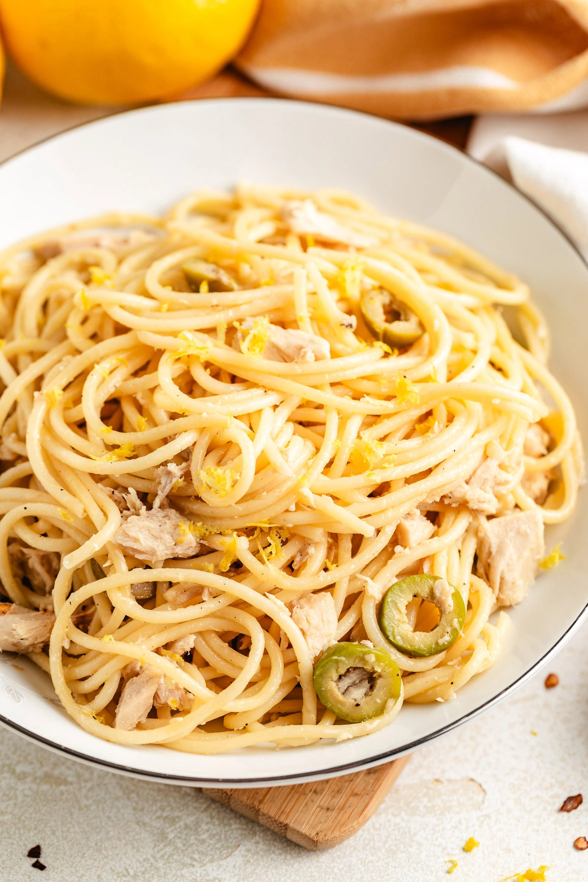 Overhead view of canned tuna pasta surrounded by fresh lemons and a kitchen towel.