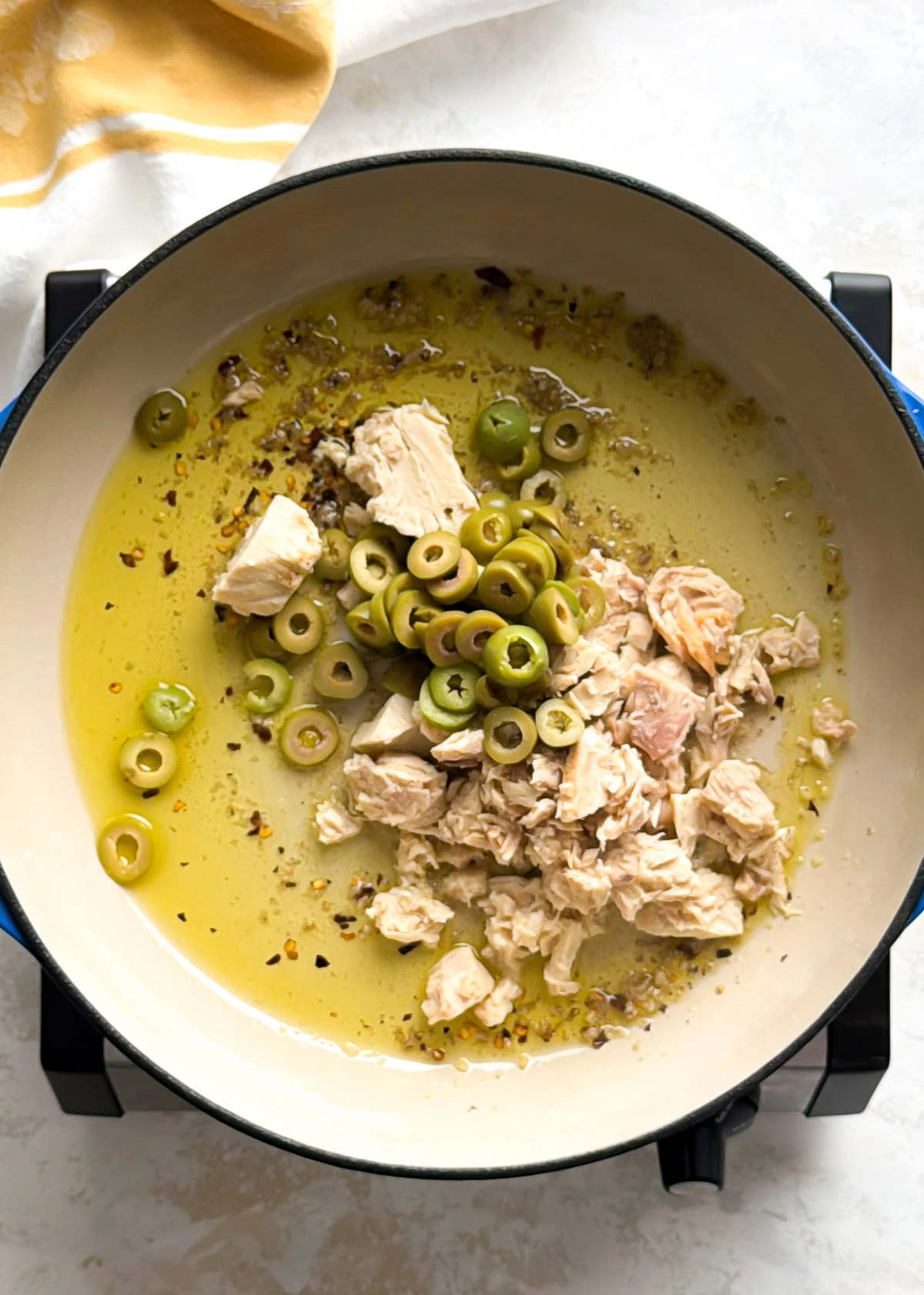 Dutch oven filled with canned tuna pasta tossed in olive oil sauce.