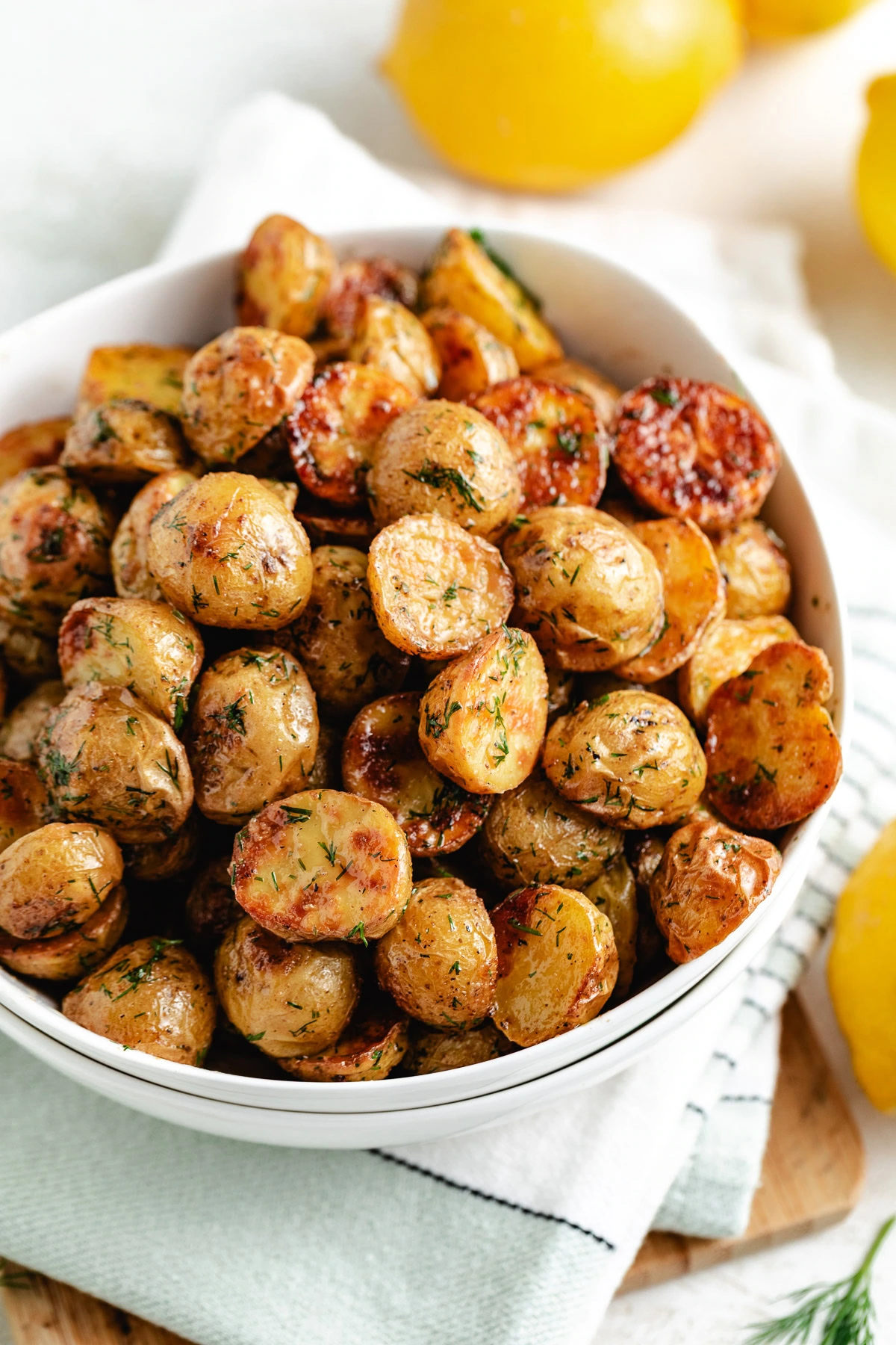 Close-up of crispy dill potatoes in a white bowl.