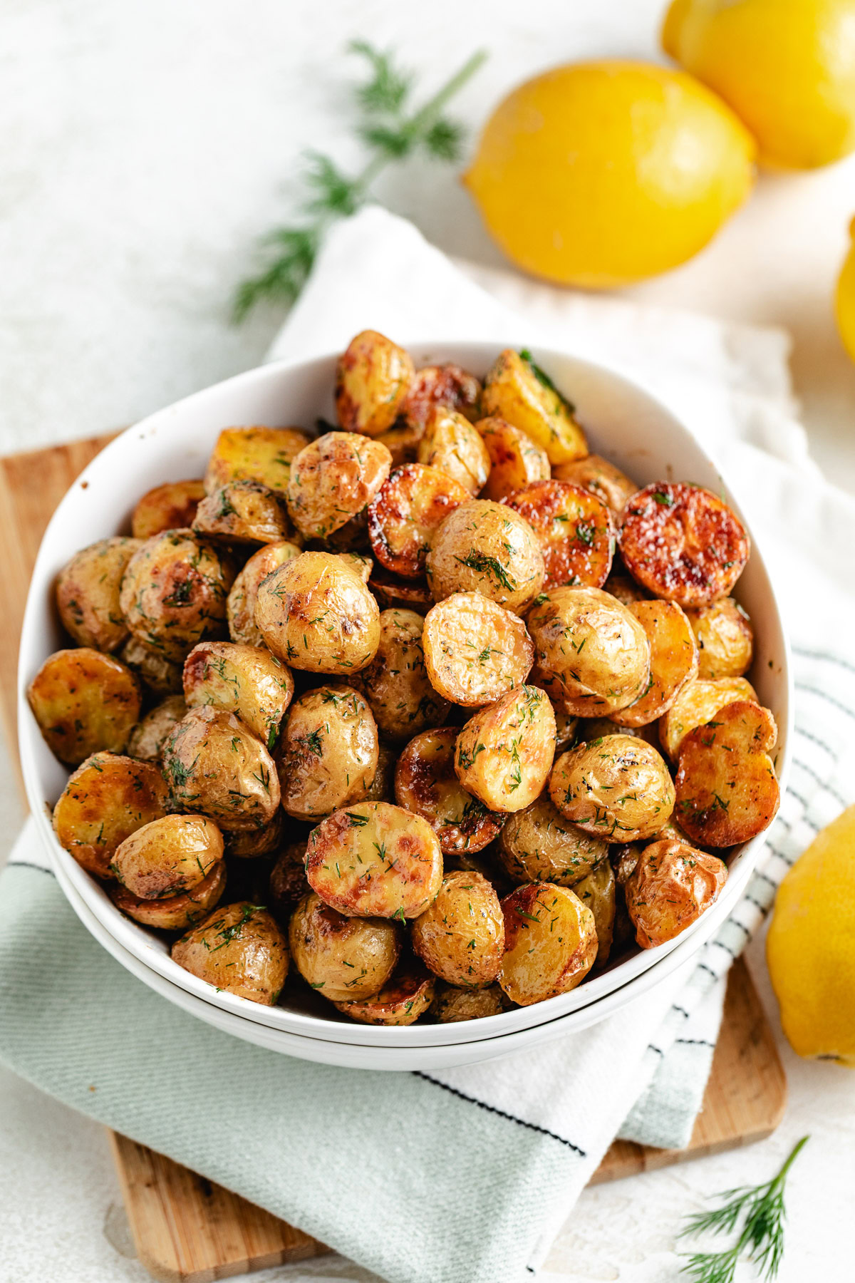 Dill potatoes served in a bowl with lemons nearby.