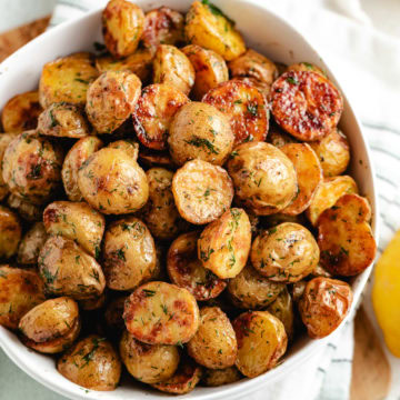 Bowl of dill potatoes with lemon in the background.