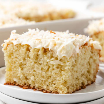 A slice of coconut cake with cream cheese frosting.