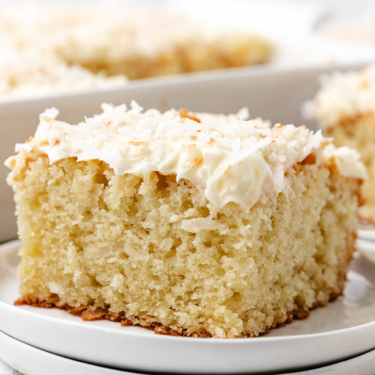 A slice of coconut cake with cream cheese frosting.
