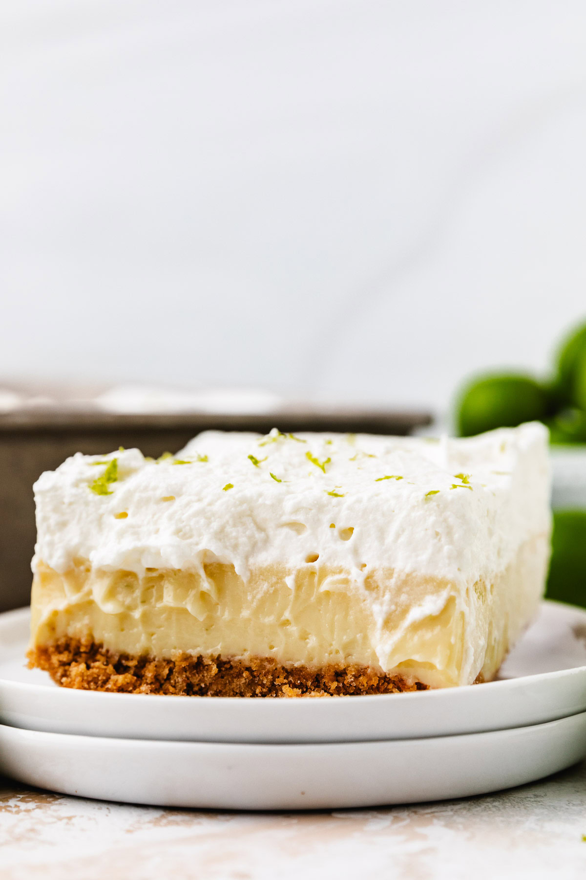 Key lime pie bar on a stack of white plates.